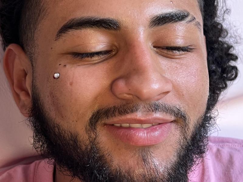Man with eyes closed with piercing on cheek